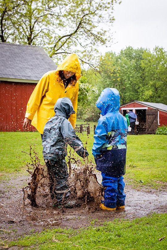 Jenny Peterson jumping in a mud puddle in the rain with two kids